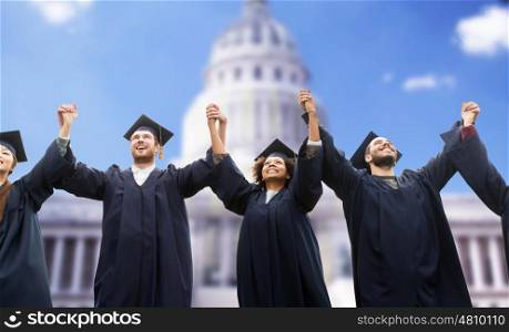 education, graduation and people concept - group of happy international students in mortar boards and bachelor gowns celebrating success over american white house background