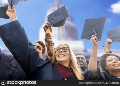 education, graduation and people concept - group of happy international students in bachelor gowns waving mortar boards or hats over american white house background
