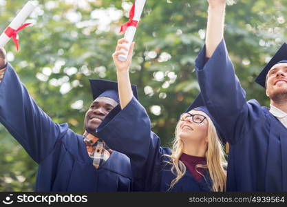 education, graduation and people concept - group of happy international students in mortar boards and bachelor gowns with diplomas celebrating success. happy students in mortar boards with diplomas