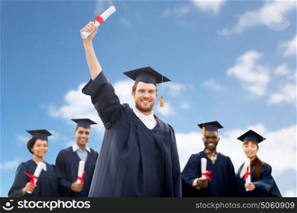 education, graduation and people concept - group of happy international students in mortar boards and bachelor gowns with diplomas over blue sky and clouds background. students or bachelors with diplomas over blue sky