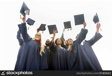 education, graduation and people concept - group of happy international students in bachelor gowns throwing mortar boards up. happy students throwing mortar boards up