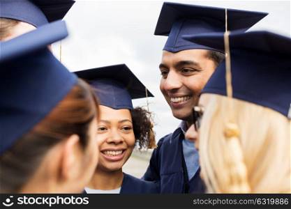 education, graduation and people concept - group of happy international students in mortar boards and bachelor gowns outdoors. happy students or bachelors in mortar boards