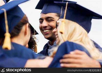 education, graduation and people concept - group of happy international students in mortar boards and bachelor gowns hugging outdoors. happy students or bachelors in mortar boards