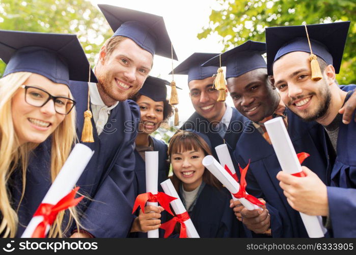 education, graduation and people concept - group of happy international students in mortar boards and bachelor gowns with diplomas. happy students in mortar boards with diplomas