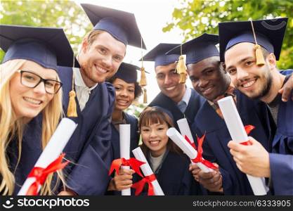 education, graduation and people concept - group of happy international students in mortar boards and bachelor gowns with diplomas. happy students in mortar boards with diplomas