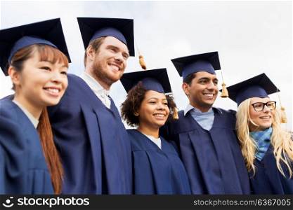 education, graduation and people concept - group of happy international students in mortar boards and bachelor gowns outdoors. happy students or bachelors in mortar boards