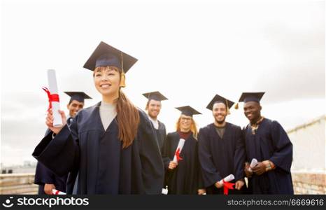 education, graduation and people concept - group of happy international students in mortar boards and bachelor gowns with diplomas. happy students in mortar boards with diplomas. happy students in mortar boards with diplomas