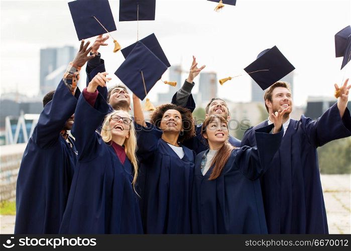 education, graduation and people concept - group of happy international students in bachelor gowns throwing mortar boards up in the air. happy graduates or students throwing mortar boards. happy graduates or students throwing mortar boards