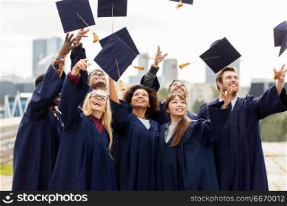 education, graduation and people concept - group of happy international students in bachelor gowns throwing mortar boards up in the air. happy graduates or students throwing mortar boards. happy graduates or students throwing mortar boards