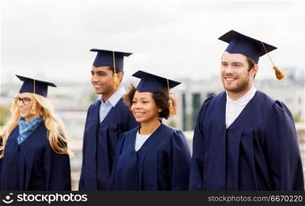 education, graduation and people concept - group of happy international students in mortar boards and bachelor gowns outdoors. happy students or bachelors in mortar boards. happy students or bachelors in mortar boards