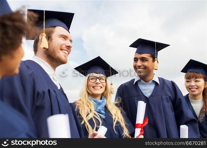 education, graduation and people concept - group of happy international students in mortar boards and bachelor gowns with diplomas. happy students in mortar boards with diplomas. happy students in mortar boards with diplomas
