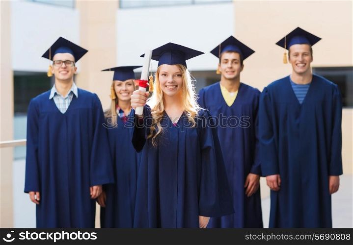 education, graduation and people concept - group of smiling students in mortarboards and gowns with diploma outdoors