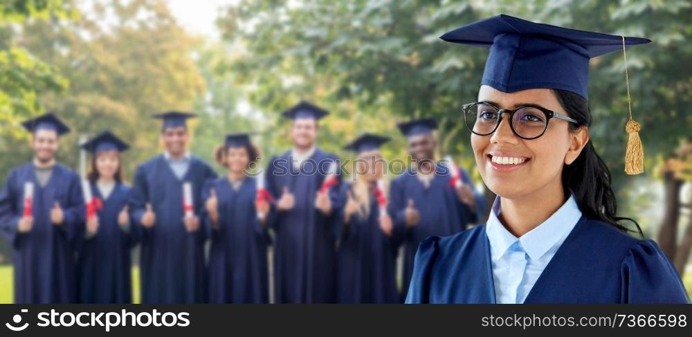 education, graduation and people concept - happy female graduate student in mortarboard and bachelor gown over group of classmates in summer park background. happy female graduate student in mortarboard