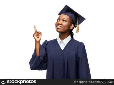 education, graduation and people concept - happy graduate student woman in mortarboard and bachelor gown pointing finger up over white background. happy female graduate student in mortarboard