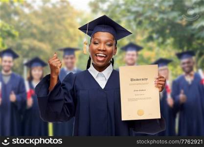 education, graduation and people concept - happy graduate student woman in mortarboard and bachelor gown showing diploma of university and making winning gesture over group of people on background. happy female graduate student with diploma