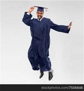 education, graduation and people concept - happy indian male graduate student in mortar board and bachelor gown celebrating success and jumping over grey background. happy male indian graduate student jumping