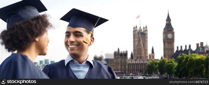 education, graduation and people concept - happy international students in mortar boards and bachelor gowns over london city background