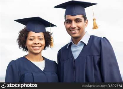 education, graduation and people concept - happy international students in mortar boards and bachelor gowns outdoors