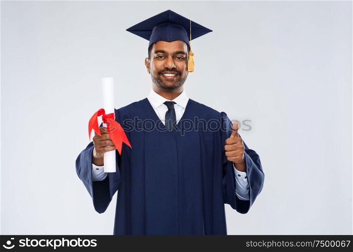 education, graduation and people concept - happy smiling indian male graduate student in mortar board and bachelor gown with diploma showing thumbs up over grey background. male graduate student in mortar board with diploma