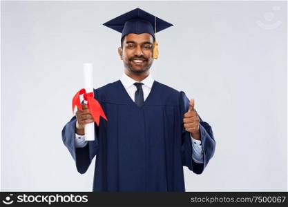 education, graduation and people concept - happy smiling indian male graduate student in mortar board and bachelor gown with diploma showing thumbs up over grey background. male graduate student in mortar board with diploma