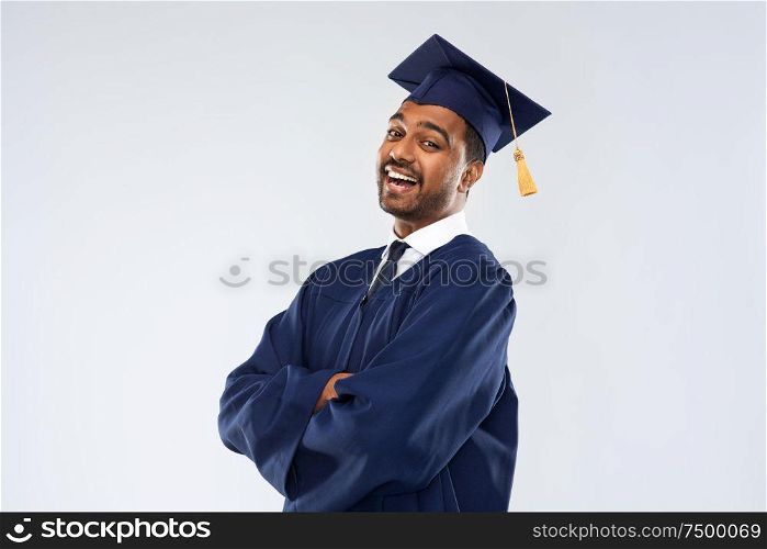 education, graduation and people concept - happy smiling indian male graduate student in mortar board and bachelor gown over grey background. happy indian graduate student in mortar board