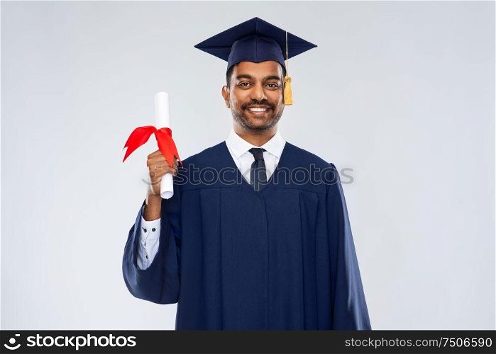 education, graduation and people concept - happy smiling indian male graduate student in mortar board and bachelor gown with diploma over grey background. male graduate student in mortar board with diploma