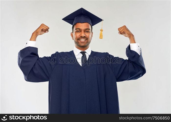 education, graduation and people concept - happy smiling indian male graduate student in mortar board and bachelor gown celebrating success over grey background. happy indian graduate student in mortar board