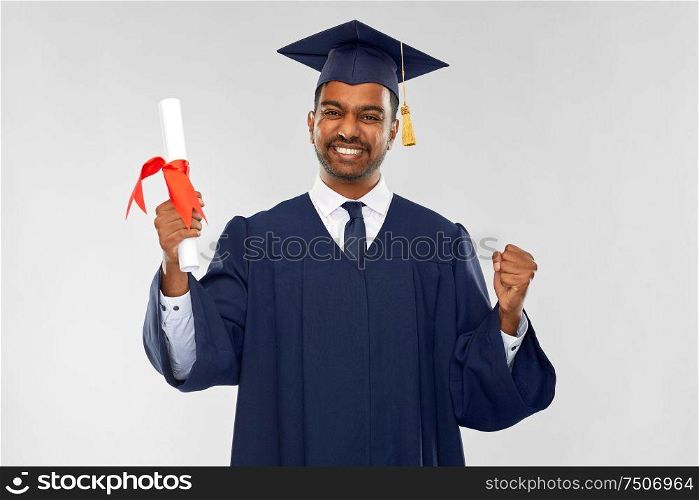 education, graduation and people concept - happy smiling indian male graduate student in mortar board and bachelor gown with diploma celebrating success over grey background. happy graduate student in mortarboard with diploma