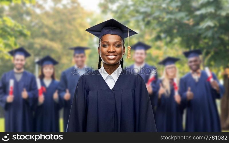 education, graduation and people concept - portrait of happy graduate student woman in mortarboard and bachelor gown over group of people on background. happy female graduate student in mortarboard