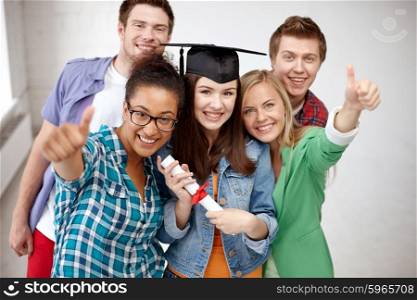 education, graduation, gesture and people concept - group of smiling students in mortarboard with diploma showing thumbs up