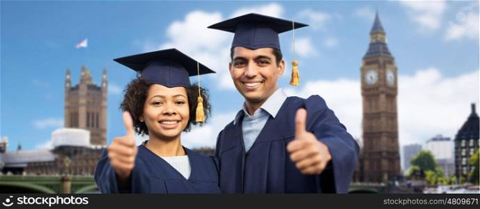 education, graduation, gesture and people concept - happy international students in mortar boards and bachelor gowns showing thumbs up over london city background