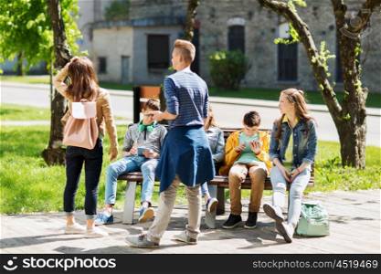 education, high school and people concept - group of happy teenage students with tablet pc computers sitting on bench at campus yard