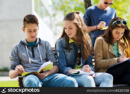 education, high school and people concept - group of happy teenage students with notebooks learning at campus yard