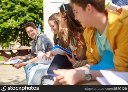 education, high school and people concept - group of happy teenage students with notebooks learning at campus yard