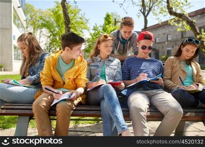 education, high school and people concept - group of happy teenage students with notebooks learning at campus yard