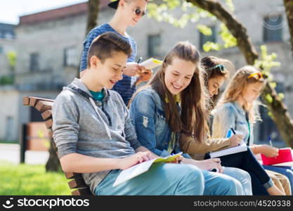 education, high school and people concept - group of happy teenage students with notebooks learning at campus yard