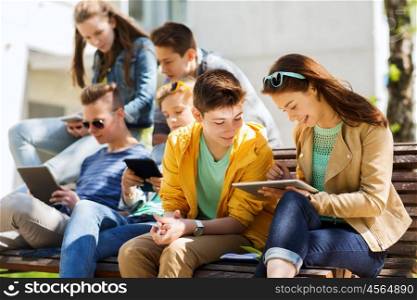 education, high school and people concept - group of happy teenage students with with tablet pc computers at campus yard