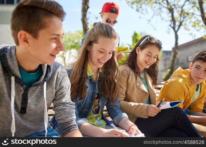 education, high school and people concept - group of happy teenage students with notebooks learning at campus yard