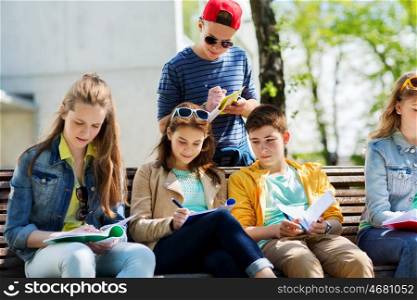education, high school and people concept - group of happy teenage students with notebooks learning at campus yard