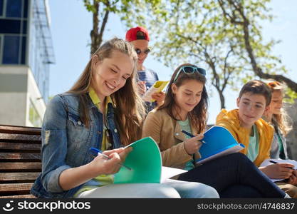 education, high school and people concept - group of happy teenage students with notebooks learning at campus yard