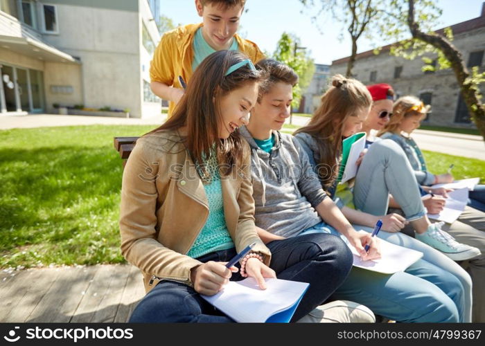 education, high school and people concept - group of happy teenage students with notebooks learning at campus yard