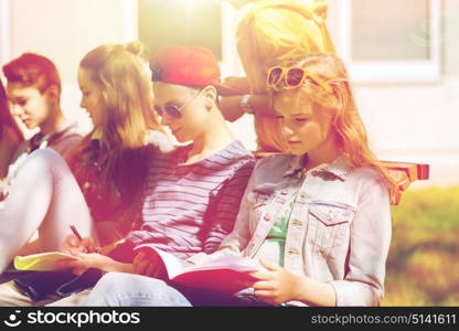 education, high school and people concept - group of happy teenage students with notebooks learning at campus yard. group of students with notebooks at school yard