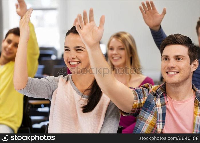 education, high school and people concept - group of smiling students raising hand in lecture hall. group of smiling students in lecture hall