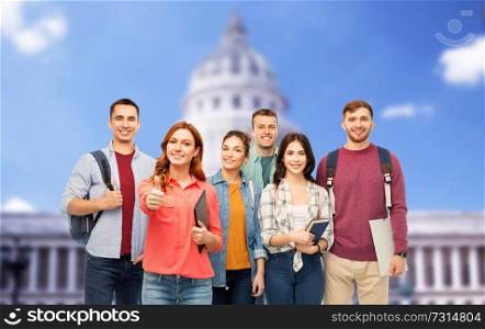 education, high school and people concept - group of smiling students with books showing thumbs up over capitol building background. students showing thumbs up over capitol building