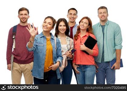 education, high school and people concept - group of smiling students with books waving hands over white background. group of students with books and school bags