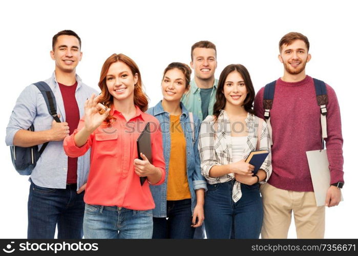 education, high school and people concept - group of smiling students with books showing ok hand sign over white background. group of smiling students showing ok hand sign