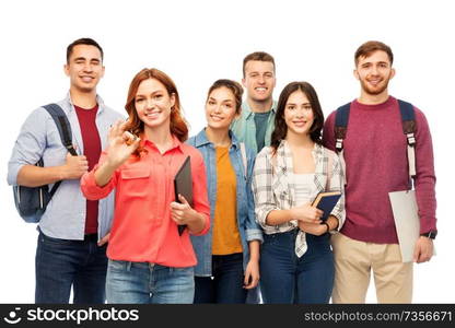 education, high school and people concept - group of smiling students with books showing ok hand sign over white background. group of smiling students showing ok hand sign