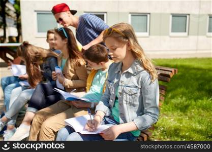 education, high school and people concept - group of teenage students with notebooks learning at campus yard