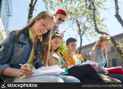 education, high school and people concept - group of teenage students with notebooks learning at campus yard