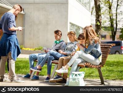 education, high school and people concept - group of teenage students with tablet pc computers sitting on bench at campus yard